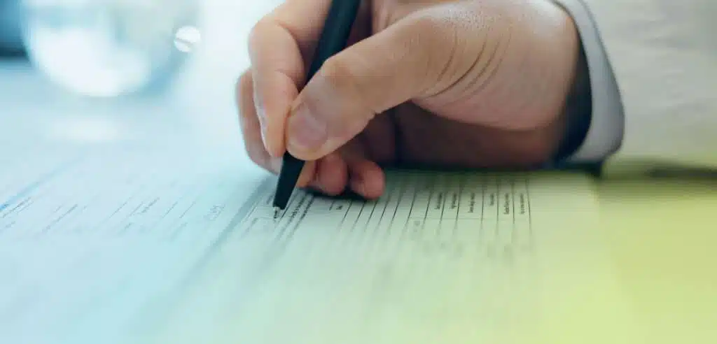 Eine Person füllt Dokumente aus, was den Prozess des Ausfüllens eines Fördermittelantrags darstellt